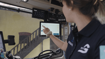 Eine Frau sitzt in einem Traktor und zeigt mit dem Finger auf das DuxAlpha Display. 